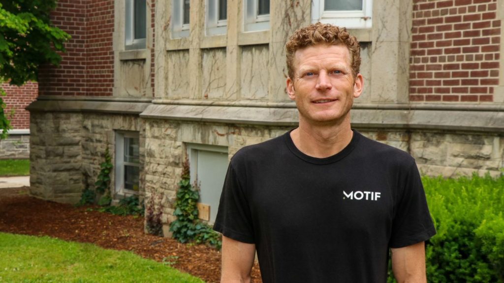 A man standing outside with motifs lab shirt on.