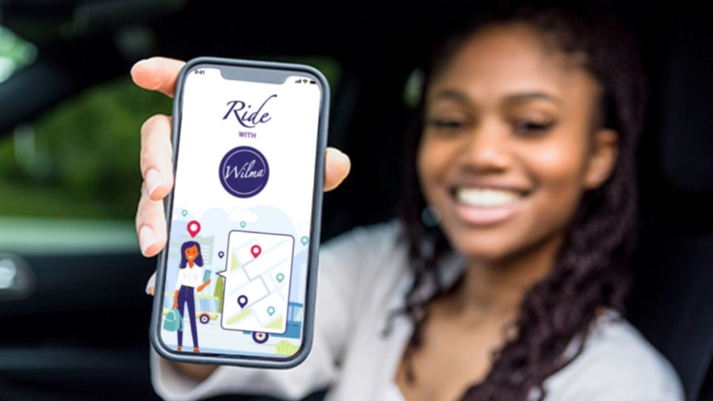 A woman showing her phone screen with the Wilma app loaded. 