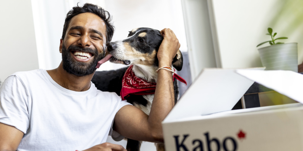 A man petting his dog while his dog licks him. The image also contains a kabo box with their company logo.